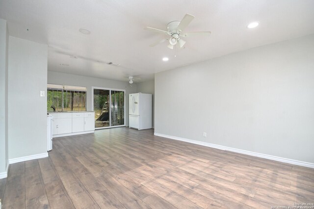 unfurnished living room featuring wood-type flooring, ceiling fan, and sink