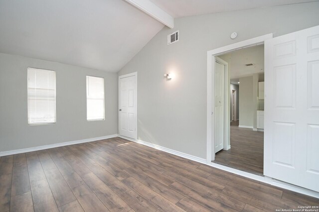 empty room with dark hardwood / wood-style flooring and lofted ceiling with beams