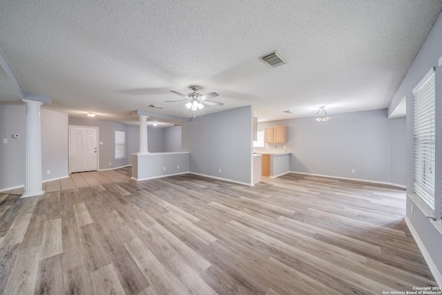 unfurnished living room featuring ceiling fan, light hardwood / wood-style floors, and decorative columns