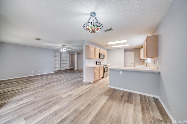 kitchen featuring stainless steel appliances, kitchen peninsula, decorative light fixtures, a textured ceiling, and light brown cabinetry