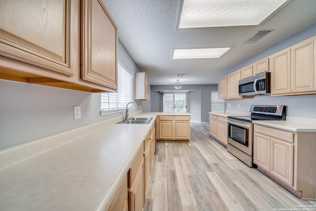 kitchen featuring sink, light brown cabinets, stainless steel appliances, light hardwood / wood-style floors, and a textured ceiling