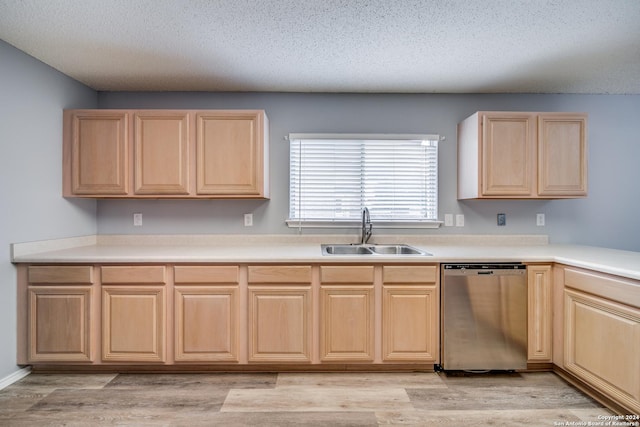 kitchen featuring stainless steel dishwasher, sink, light brown cabinetry, and a textured ceiling