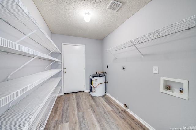 washroom with hookup for a washing machine, light wood-type flooring, a textured ceiling, electric dryer hookup, and water heater