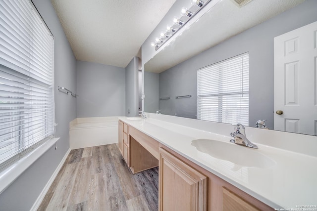 bathroom featuring hardwood / wood-style flooring, vanity, a bathing tub, and a textured ceiling