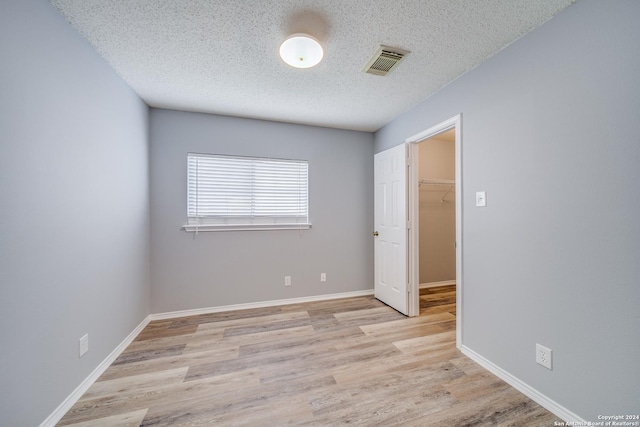 spare room featuring light hardwood / wood-style floors and a textured ceiling