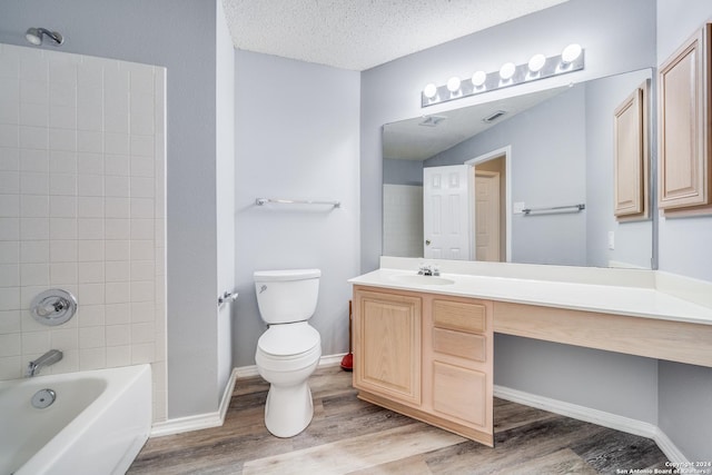 full bathroom with vanity, tiled shower / bath combo, toilet, a textured ceiling, and wood-type flooring