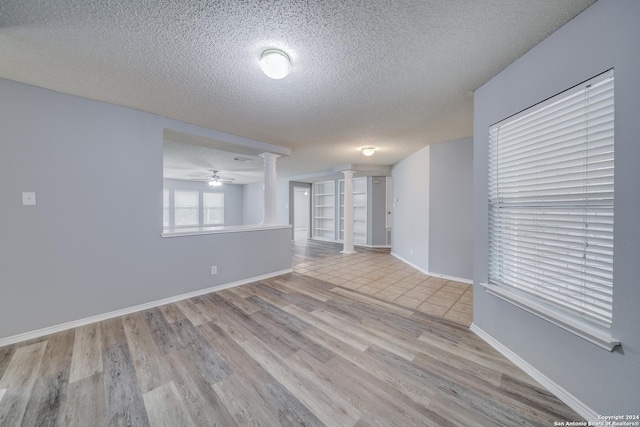 spare room featuring decorative columns, ceiling fan, light hardwood / wood-style floors, and a textured ceiling