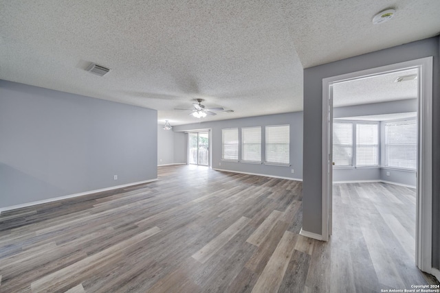 unfurnished living room featuring ceiling fan, plenty of natural light, a textured ceiling, and light hardwood / wood-style flooring