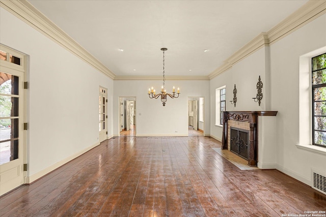 unfurnished living room with an inviting chandelier, hardwood / wood-style flooring, ornamental molding, and a tile fireplace