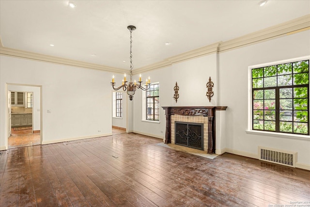 unfurnished living room featuring wood-type flooring, crown molding, an inviting chandelier, and a fireplace