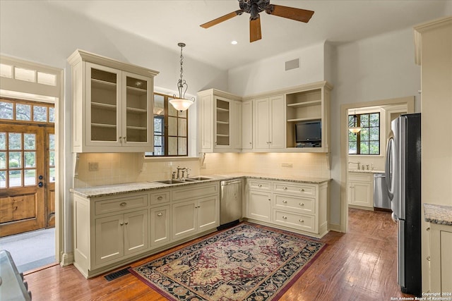 kitchen featuring hanging light fixtures, stainless steel appliances, sink, and light wood-type flooring