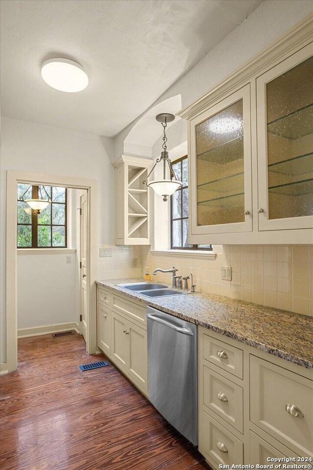 kitchen featuring dark wood-type flooring, sink, hanging light fixtures, dishwasher, and backsplash