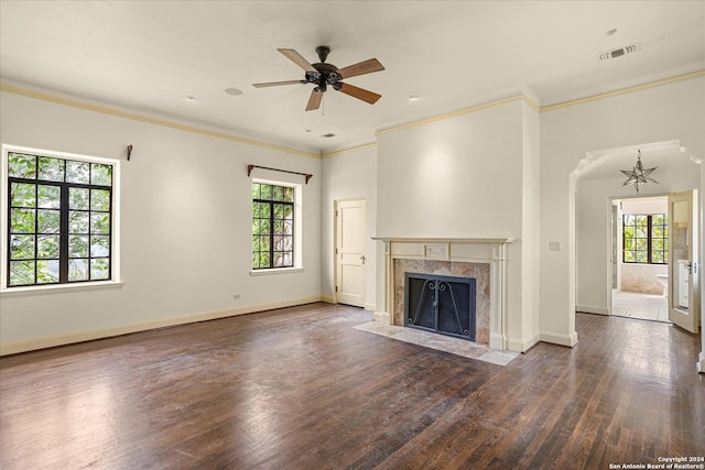 unfurnished living room featuring dark wood-type flooring, a high end fireplace, ornamental molding, and ceiling fan