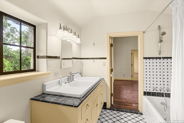 bathroom with lofted ceiling, vanity, tile patterned floors, and tub / shower combination