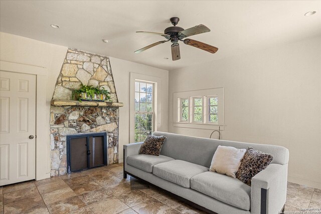 living room featuring a stone fireplace and ceiling fan