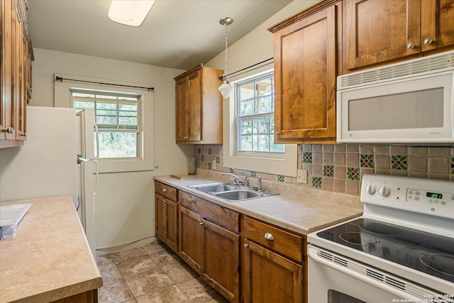 kitchen featuring sink, white appliances, decorative light fixtures, and backsplash