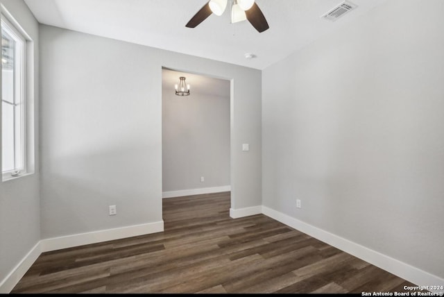 spare room with dark hardwood / wood-style flooring and ceiling fan with notable chandelier