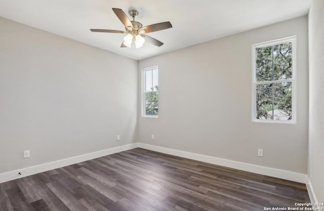 unfurnished room featuring a wealth of natural light, ceiling fan, and dark wood-type flooring