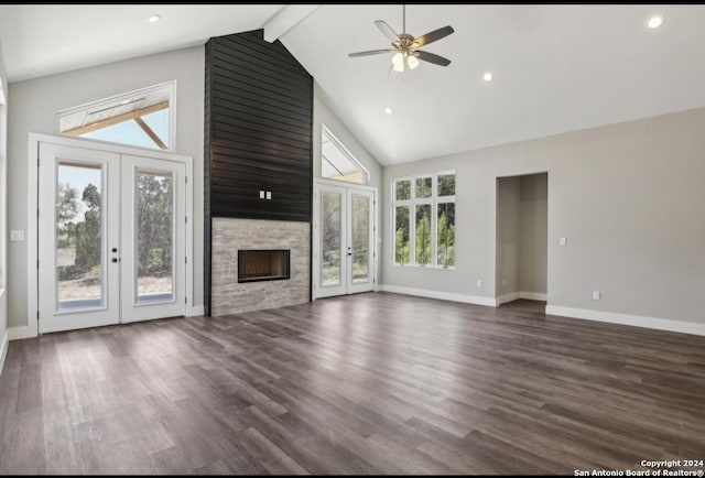 unfurnished living room featuring french doors, dark hardwood / wood-style flooring, beam ceiling, high vaulted ceiling, and a stone fireplace