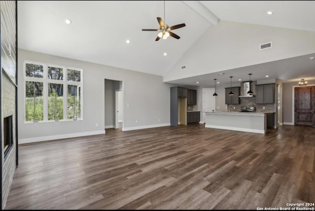 unfurnished living room with beamed ceiling, dark hardwood / wood-style floors, high vaulted ceiling, and ceiling fan