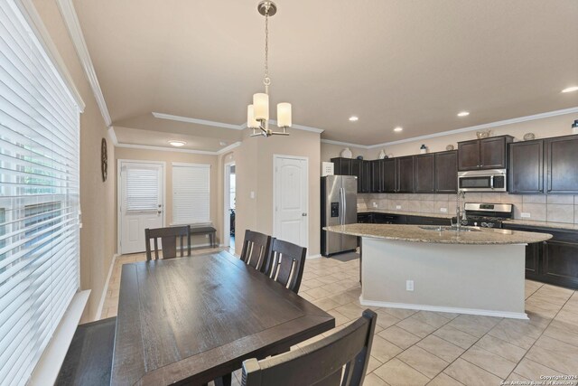 tiled dining space with ornamental molding, a notable chandelier, and sink