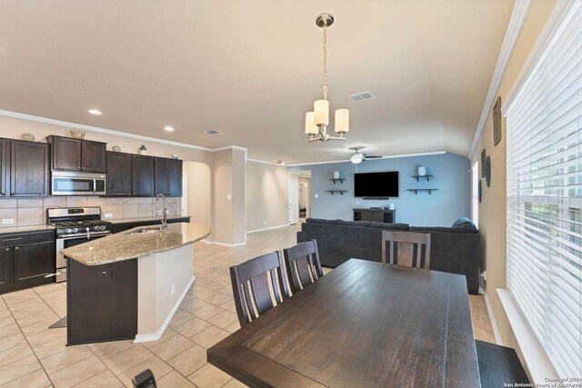 kitchen featuring backsplash, a center island with sink, sink, hanging light fixtures, and stainless steel appliances