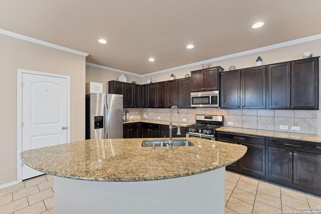 kitchen with light tile patterned floors, sink, stainless steel appliances, and an island with sink