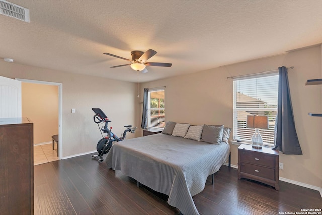 bedroom with multiple windows, a textured ceiling, dark hardwood / wood-style flooring, and ceiling fan