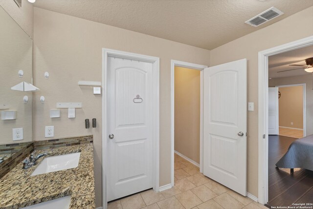 bathroom with tile patterned floors, ceiling fan, vanity, and a textured ceiling