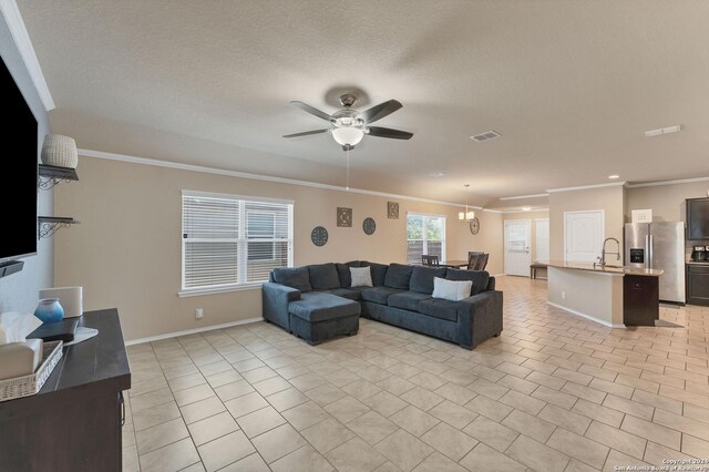 tiled living room featuring a textured ceiling, ceiling fan, sink, and crown molding