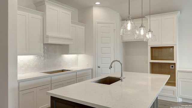 kitchen featuring pendant lighting, a kitchen island with sink, sink, black electric cooktop, and white cabinetry