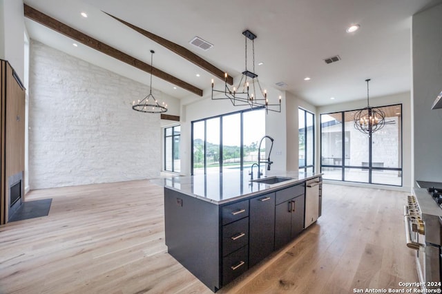 kitchen with decorative light fixtures, beamed ceiling, sink, a chandelier, and a large island with sink