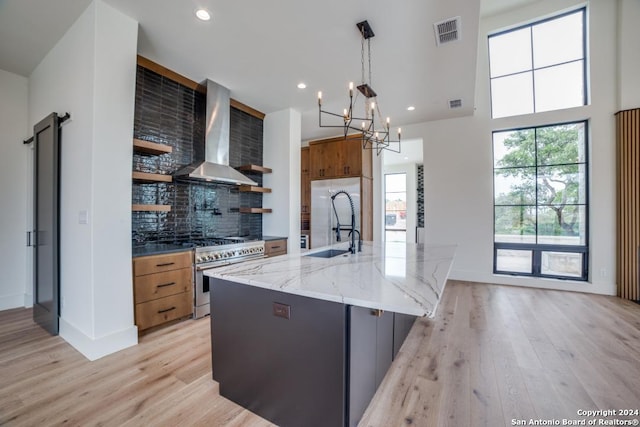 kitchen with backsplash, hanging light fixtures, high end appliances, a large island, and wall chimney exhaust hood