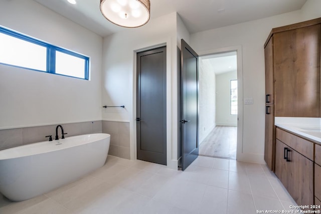 bathroom featuring vanity, tile patterned flooring, a washtub, and a wealth of natural light