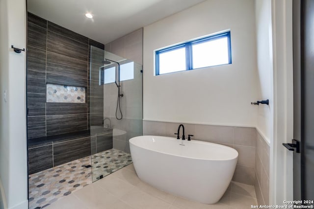 bathroom with tile walls, tile patterned flooring, and plus walk in shower