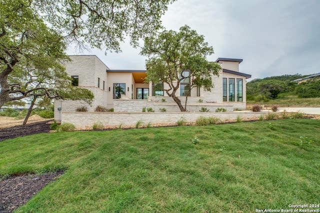 rear view of property with a lawn and stucco siding