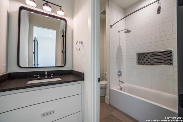 full bathroom featuring tiled shower / bath, vanity, toilet, and tile patterned flooring