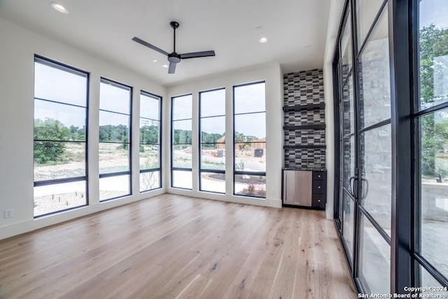 unfurnished room featuring ceiling fan, plenty of natural light, and light wood-type flooring