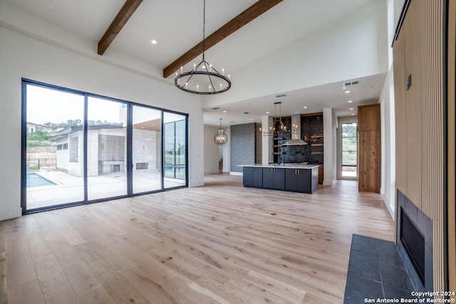 unfurnished living room with beam ceiling, high vaulted ceiling, an inviting chandelier, and light hardwood / wood-style flooring