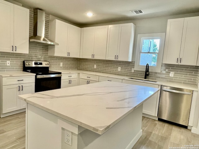 kitchen with wall chimney range hood, white cabinetry, stainless steel appliances, sink, and tasteful backsplash