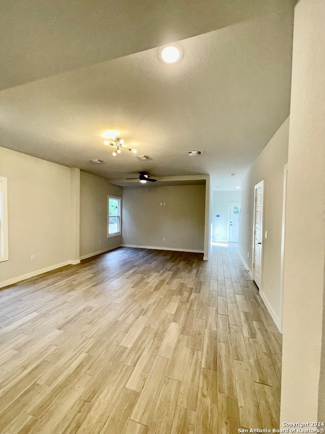 empty room with ceiling fan and light hardwood / wood-style flooring