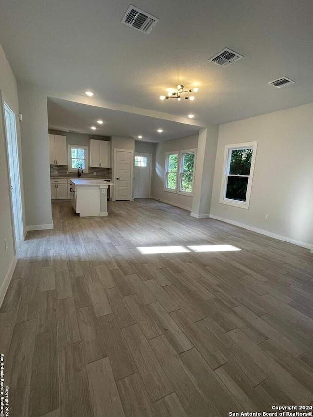 unfurnished living room featuring sink and light hardwood / wood-style flooring