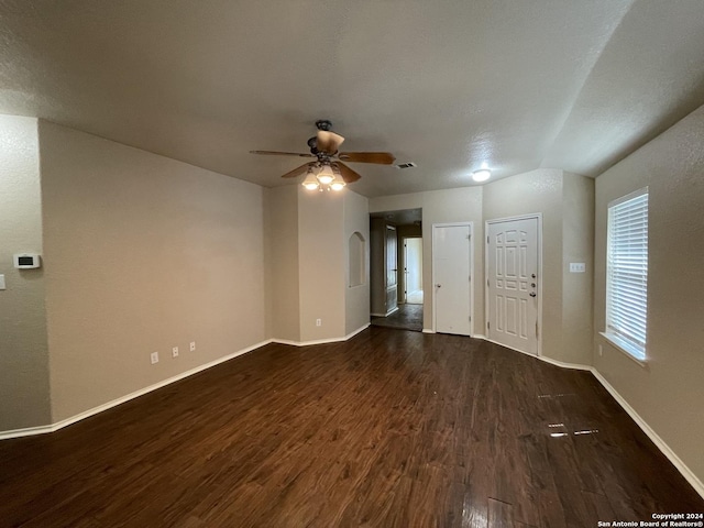 empty room featuring a textured ceiling, dark hardwood / wood-style flooring, vaulted ceiling, and ceiling fan