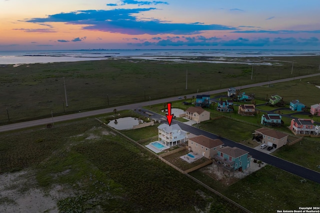 aerial view at dusk featuring a water view and a rural view