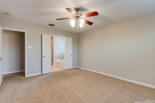 unfurnished bedroom featuring ceiling fan, ensuite bathroom, and light colored carpet