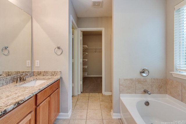 bathroom with tile patterned flooring, vanity, and a tub to relax in