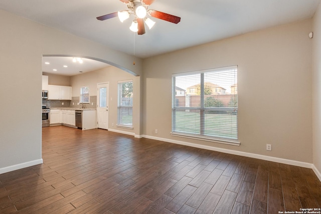 unfurnished living room featuring dark hardwood / wood-style flooring, ceiling fan, and sink