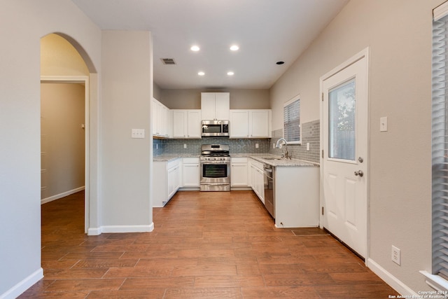 kitchen featuring light stone countertops, appliances with stainless steel finishes, tasteful backsplash, sink, and white cabinets