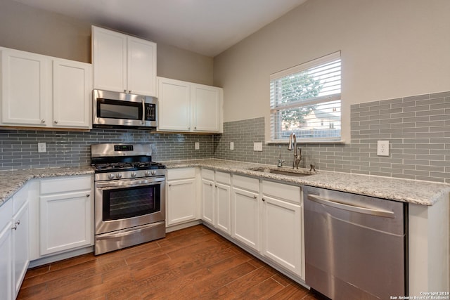 kitchen with sink, dark hardwood / wood-style flooring, backsplash, white cabinets, and appliances with stainless steel finishes