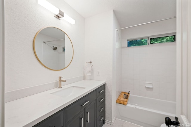 bathroom with tile patterned flooring, tiled shower / bath, and vanity